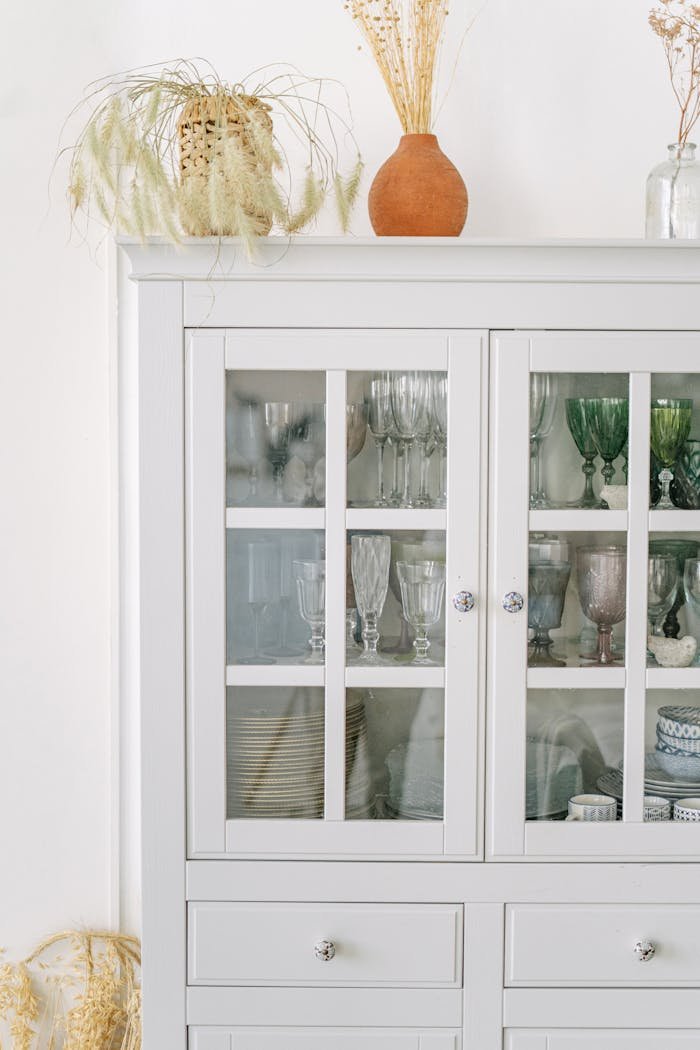 Minimalist white cabinet with elegant glassware and decor, adding a touch of sophistication.